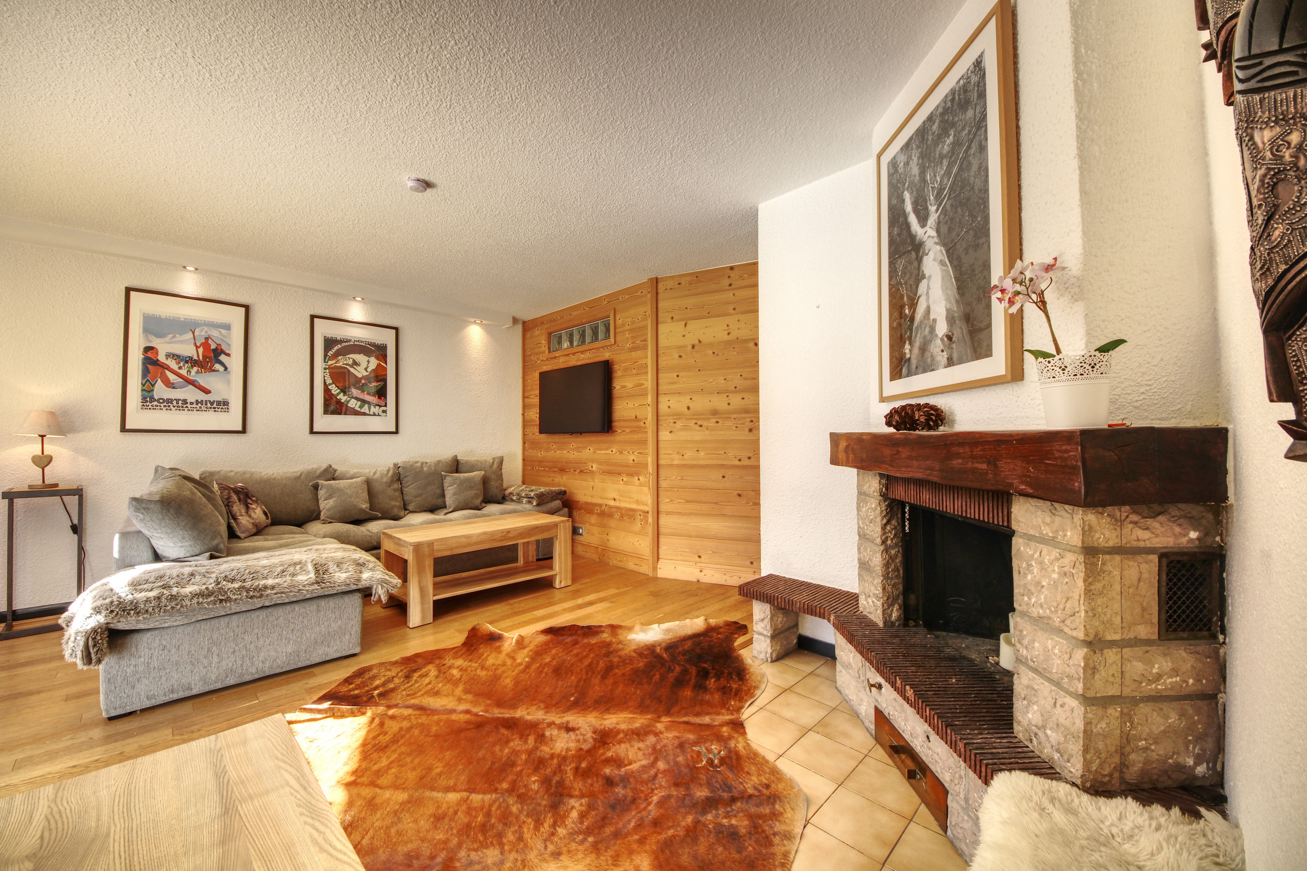 Grand salon avec cheminée centrale en pierre et canapés confortables